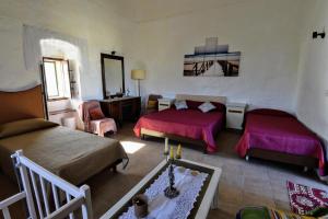 a living room with two beds and a table at 400YR Farmhouse in Xaghra Gozo - Entire Farmhouse in Tal-Barmil