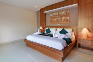 - une chambre avec un grand lit et une peinture murale dans l'établissement Villa Wananta, à Ubud