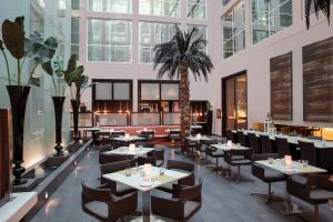 a restaurant with tables and chairs and a palm tree at Centro Barsha - by Rotana in Dubai