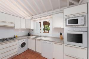 a white kitchen with white cabinets and appliances at Superior G: private pool & concierge in Icod de los Vinos