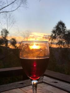 a glass of wine sitting on a table with the sunset at Chalés Pôr do Sol in Gonçalves