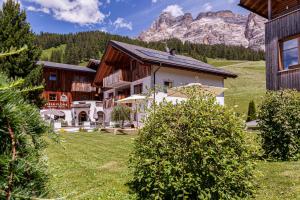 a house with a mountain in the background at Villa Flora Mountain Lodges in San Cassiano