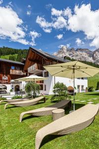 a group of chairs and an umbrella in the grass at Villa Flora Mountain Lodges in San Cassiano