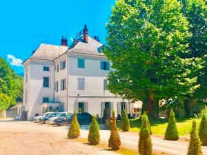 uma grande casa branca com carros estacionados em frente em Hôtel Restaurant Le Repère em Vizille