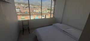 een slaapkamer met een bed, een stoel en een raam bij Hotel Mi Gloria in Tunja