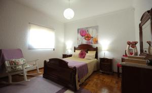 a bedroom with a bed and a chair and a window at Casa Flor do Campo in Celorico de Basto