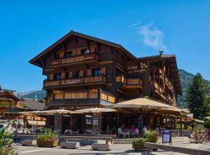 a large wooden building with umbrellas in front of it at Lovely 2 Bed Apartment in Morzine with garden in Morzine