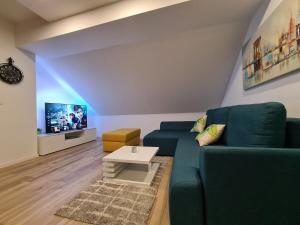 uma sala de estar com um sofá verde e uma televisão em Boutique Apartments Nikola Tesla em Rakovica