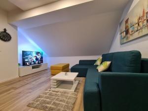 sala de estar con sofá verde y TV en Boutique Apartments Nikola Tesla, en Rakovica