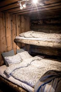 two beds in a room with wooden walls at Varjokelo in Ruka