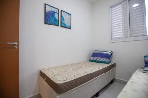 a bedroom with a bed with two pillows on it at Apto 2 Dorms, 1 Suíte, JP2 Home Resort Ubatuba - Churrasqueira Gourmet, Ar Condicionado, Piscinas, Sauna e Salão de Jogos in Ubatuba +17 photos