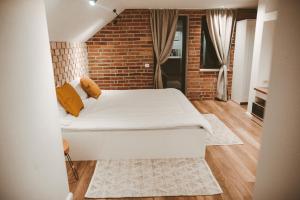 a bedroom with a white bed and a brick wall at Vila Casa din gradina in Voivodeni +33 photos