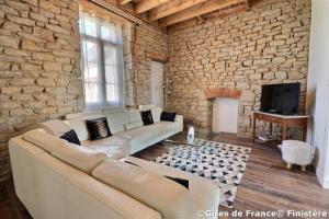 a living room with a couch and a brick wall at Maison de famille Penmarch in Penmarch