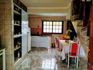 a kitchen with a table and red chairs in a kitchen at Casa da Tuca in São João del Rei