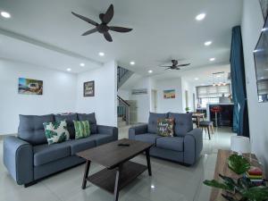 - un salon avec deux canapés bleus et une table dans l'établissement Desaru Comfy Home with Netflix Near Beach, Waterpark & BBQ, à Bandar Penawar