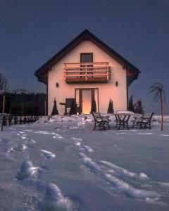 dom na śniegu z ławkami przed nim w obiekcie Orawski Letniskowiec w mieście Zubrzyca Dolna