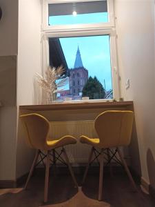 una ventana con 2 sillas frente a un escritorio con vistas en Apartament CCH - Biskupia, en Chełmno