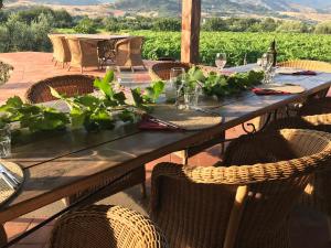 une table en bois avec des chaises et une table avec des plantes. dans l'établissement Tenuta Madonnina, à Castiglione di Sicilia