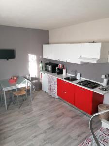 una piccola cucina con armadi rossi e tavolo di La Casa delle Rondini a Montelupo Fiorentino