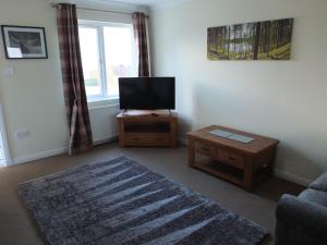 uma sala de estar com uma televisão de ecrã plano e uma mesa em No 25 Inverness - Home from Home in the Highlands em Inverness