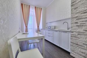 a white kitchen with a table and a sink at Апартаменты Петровские однокомнатные Трифонова 22 in Tomsk