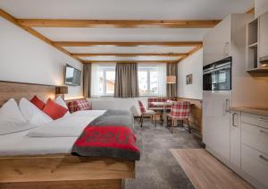 a hotel room with a bed and a table at Apartments & Garni Alpenrose in Obertauern