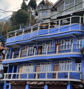 ein blaues Gebäude mit weißen Fenstern und Balkonen in der Unterkunft West Point Backpackers Hostel in Darjeeling