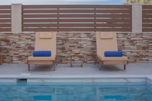 two chairs and a table next to a swimming pool at M & S Villa - 3 bedroom villa with heated pool in Pastida