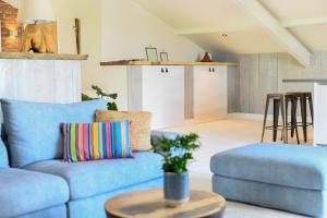 a living room with a blue couch and a table at Loft in de Polder (L) in Grootschermer