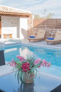 a vase of flowers sitting on a table next to a swimming pool at M & S Villa - 3 bedroom villa with heated pool in Pastida