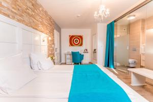 een slaapkamer met een groot wit bed met een blauwe deken bij Hotel-Restaurant Kriva Ćuprija in Mostar