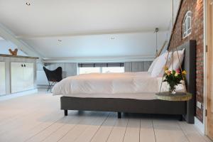 a bedroom with a large bed and a brick wall at Loft in de Polder (L) in Grootschermer