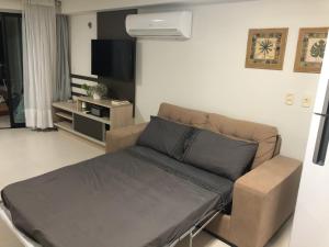a living room with a couch and a flat screen tv at Tabatinga Residence Flat Pé na Areia I in Conde