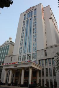 a tall white building with columns in front of it at Dynasty International Hotel Dalian in Jinzhou