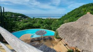 - une vue sur la piscine avec un parasol dans l'établissement OceanoMar, à Mazunte