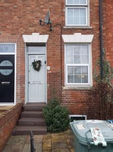 a brick house with a white door with a wreath on it at Victorian Townhouse in Banbury