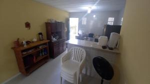 a kitchen with a counter and white chairs in a room at Casa de praia in Porto De Galinhas