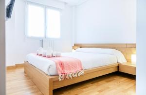 um quarto com uma cama com lençóis brancos e uma janela em Urumea 4 - Apartamento con parking em San Sebastián