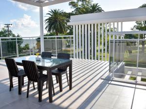 a patio with a glass table and chairs on a balcony at Casa Laguna Chascomus in Chascomús