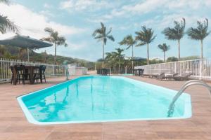 a swimming pool with palm trees in the background at Pousada Morada da Praia - Balneário Camboriú in Balneário Camboriú