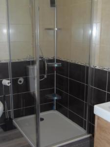 a shower with a glass door in a bathroom at petite maison de vacance in Grandcamp-Maisy
