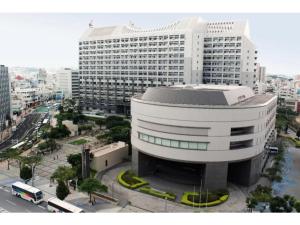 a large white building in front of a city at Hotel Kokusai Plaza - Vacation STAY 09920v in Naha
