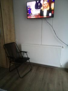 Habitación con silla y TV en la pared en Cosy Apartment, en Borjomi