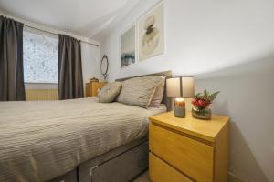 a bedroom with a bed and a dresser with a lamp at SkyCity London Bridge I Bed Apartment by Tower Bridge in London