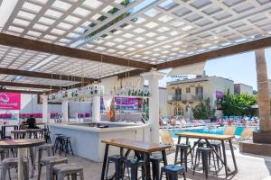 a restaurant with tables, chairs, and umbrellas at Quayside Village Hotel in Kavos