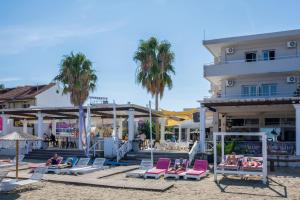 a beach with chairs and palm trees and a hotel at Quayside Village Hotel in Kavos