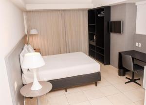 a small bedroom with a bed and a desk at Executive Hotel in Feira de Santana