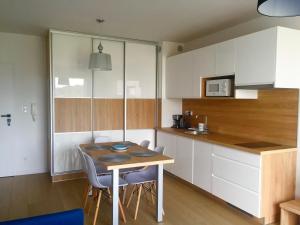 kuchnia z białymi szafkami, stołem i krzesłami w obiekcie Apartament Diuna w Grzybowie