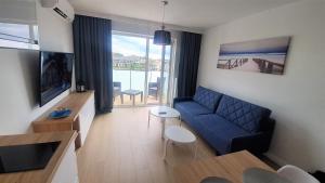 salon z niebieską kanapą i telewizorem w obiekcie Apartament Diuna w Grzybowie