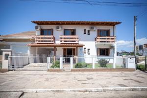 a white house with a white fence in front of it at Casa da Praia Pousada - Guesthouse in Torres